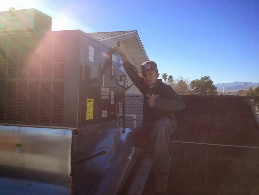 HVAC technician performing Heat Pump Repair on a rooftop unit in Commerce